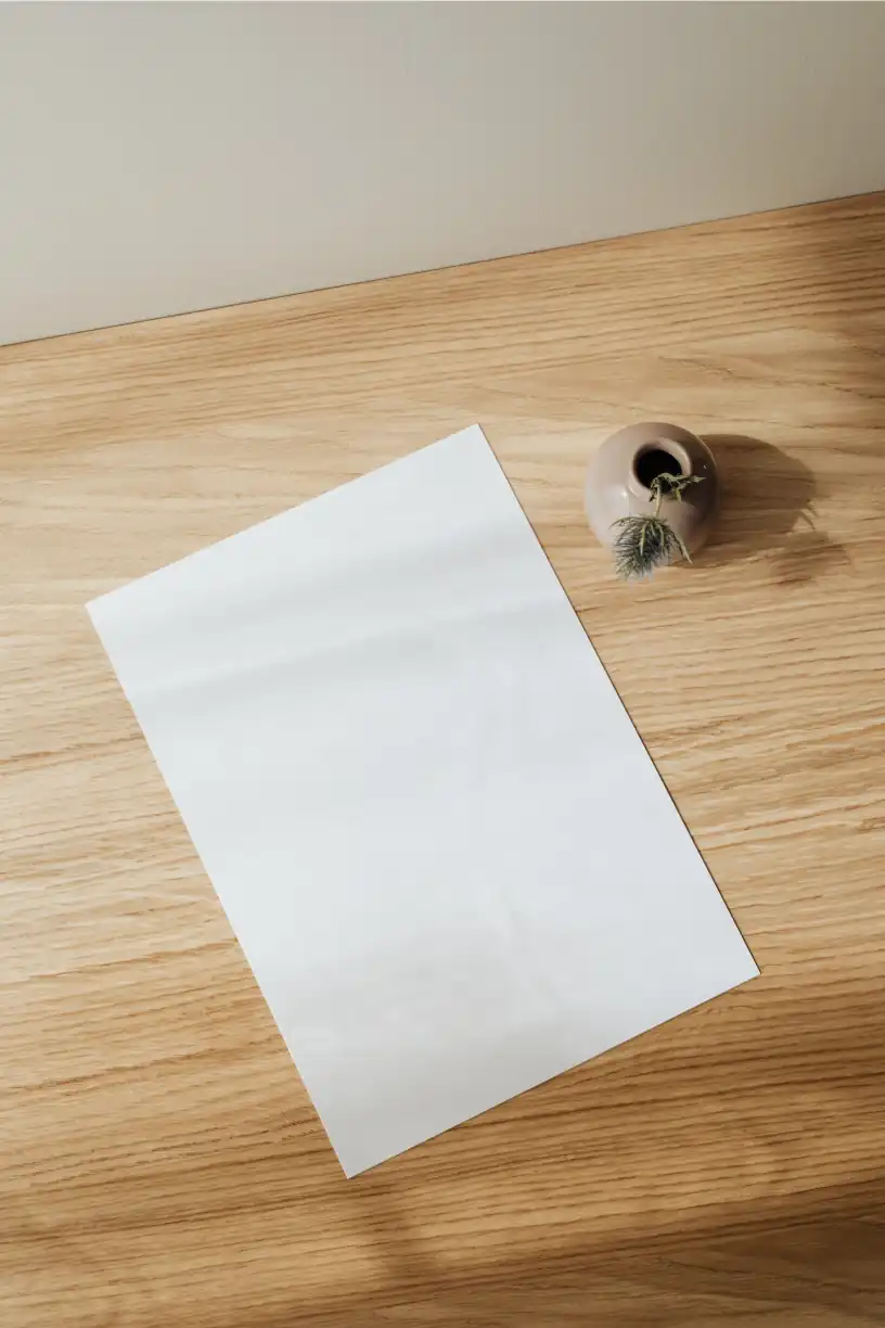 Piece of paper on a wood desk with a vase