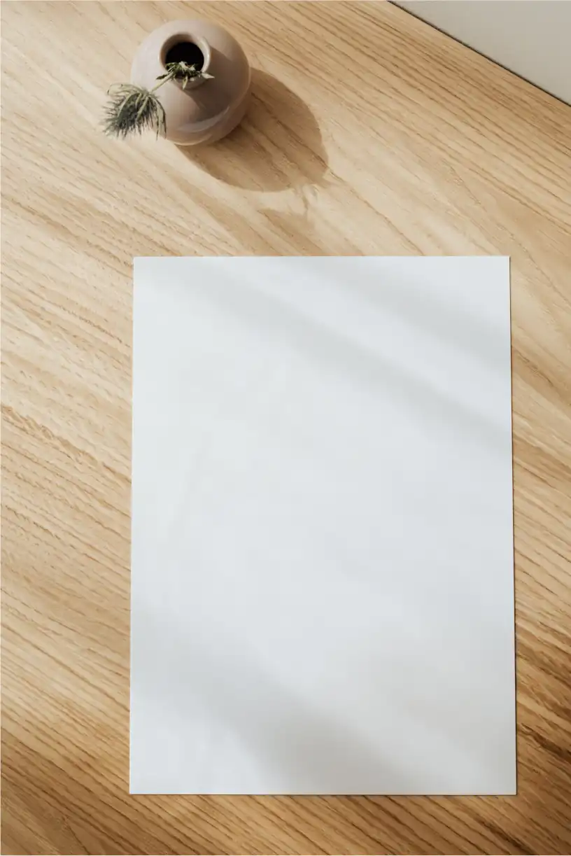 Piece of paper on a wood desk with a vase
